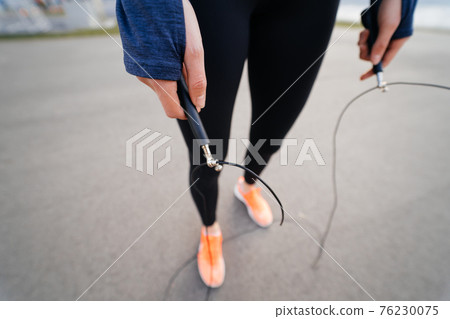 Young woman exercise with skipping rope outdoors Young woman exercise with skipping rope outdoors 76230075
