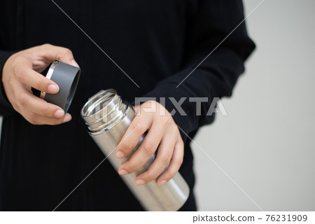 Female athlete opening the steel water bottle Female athlete opening the steel water bottle 76231909