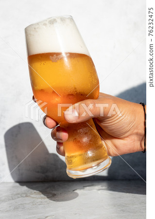 Hand holding a glass with foamy IPA beer 76232475