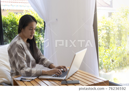 Asian woman working with laptop. Business woman busy working on laptop computer at home. Asian woman freelance online working with laptop. Business and lifestyle concept 76236592