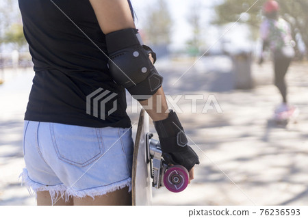 Close up on young women wear protection and hand hold skateboard, surf skate on public skate ramp park background. Free relax skateboard surf skate trendy concept. Fashion portrait of female hands Close up on young women wear protection and hand hold skateboard, surf skate on public skate ramp park background. Free relax skateboard surf skate trendy concept. Fashion portrait of female hands 76236593