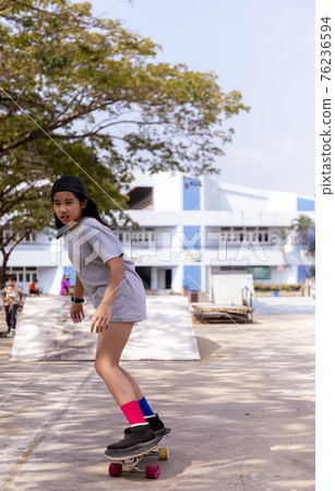 Little asian girl play surf skate board at park skate ramp outdoors on morning. Happy girl play surfskate board at park . Sport activity lifestyle concept Little asian girl play surf skate board at park skate ramp outdoors on morning. Happy girl play surfskate board at park . Sport activity lifestyle concept 76236594