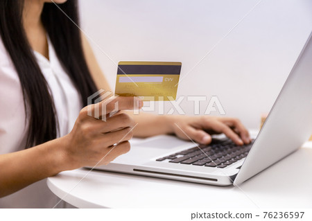 Young woman holding credit card and using laptop computer. Women working at home. Online shopping, e-commerce, internet banking, spending money, working from home concept. Technology shopping online Young woman holding credit card and using laptop computer. Women working at home. Online shopping, e-commerce, internet banking, spending money, working from home concept. Technology shopping online 76236597