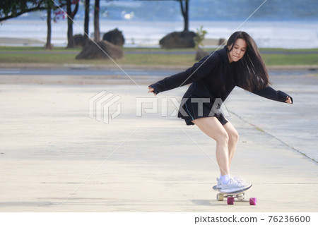 Asian women play surf skates board outdoors on beautiful summer day. Happy young women play surfskate at park on morning time. Sport activity lifestyle concept. Young women enjoy with SurfSkate board Asian women play surf skates board outdoors on beautiful summer day. Happy young women play surfskate at park on morning time. Sport activity lifestyle concept. Young women enjoy with SurfSkate board 76236600