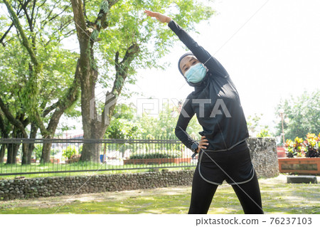 muslim woman athlete stretching and exercising her body outdoor 76237103