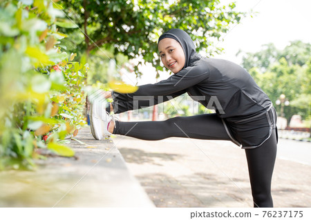 muslim asian woman strecth her leg during sport time outdoor 76237175