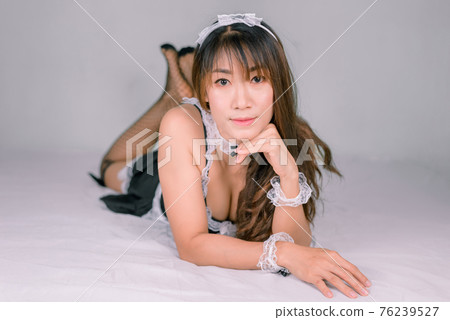 Asian woman in sexy maid dress on white bed Asian woman in sexy maid dress on white bed 76239527