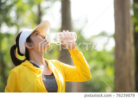 Healthy athletic asia woman is drinking pure water from the bottle refreshing herself after exercise 76239879