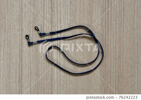 leather dark blue eyeglasses strap on a wooden background leather dark blue eyeglasses strap on a wooden background 76242223