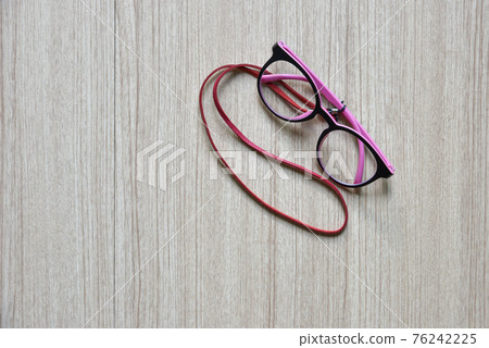 Clear Eyeglasses, Glasses pink and black Frame Vintage Style with neck strap on Wood Background Clear Eyeglasses, Glasses pink and black Frame Vintage Style with neck strap on Wood Background 76242225