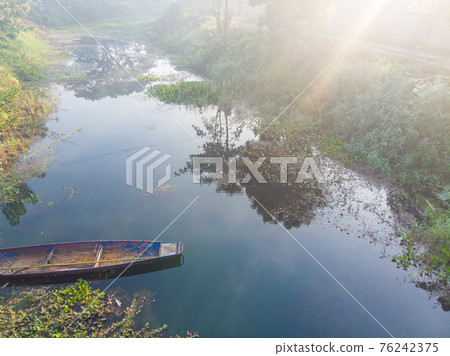 Paddle old boat on river with morning fog sunrise 76242375