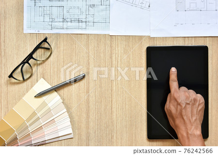 a top view of architect working desk with hand touch on equipments for drawings pens sketched idea on wood table, the concept of modern technology for architectural working with tablet a top view of architect working desk with hand touch on equipments for drawings pens sketched idea on wood table, the concept of modern technology for architectural working with tablet 76242566