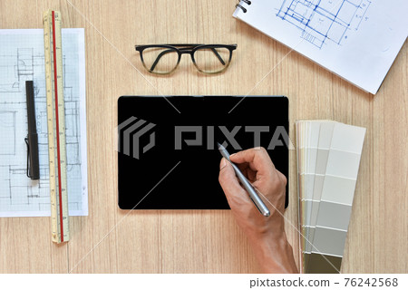 a top view of architect working desk with hand writing and draw on equipments for drawings pens sketched idea on wood table, the concept of modern technology for architectural working with tablet a top view of architect working desk with hand writing and draw on equipments for drawings pens sketched idea on wood table, the concept of modern technology for architectural working with tablet 76242568