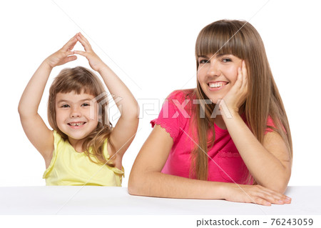 mother and little daughter are sitting at the table and smiling, the girl raised her arms above her head and folded them, as if the roof of the house, a concept of family and real estate mother and little daughter are sitting at the table and smiling, the girl raised her arms above her head and folded them, as if the roof of the house, a concept of family and real estate 76243059