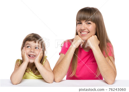 Mom and her little daughter, sitting at the table, laughing, emotions and gestures, happy girls, on a white background Mom and her little daughter, sitting at the table, laughing, emotions and gestures, happy girls, on a white background 76243060