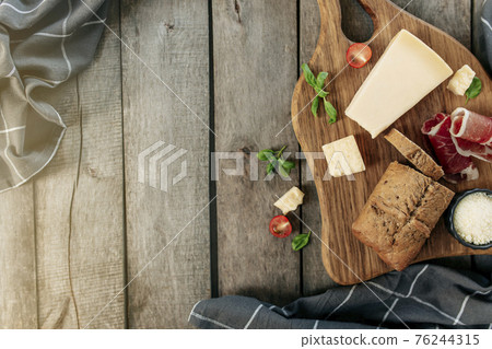 Italian cuisine concept. Parmesan Cheese, sliced ham, tomatos, basil, bread Italian cuisine concept. Parmesan Cheese, sliced ham, tomatos, basil, bread 76244315