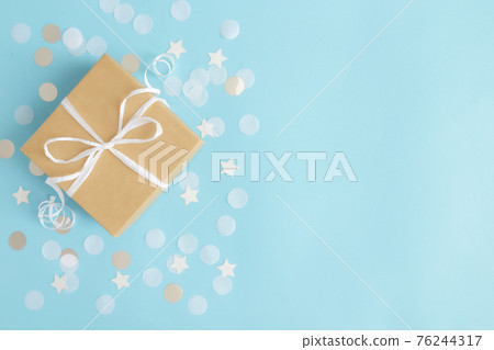 Paper gift box tied with ribbon, star and circle paper confetti or glitters 76244317