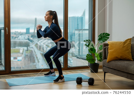 Brunette woman with brown ponytail in squat pose in lodge 76244550