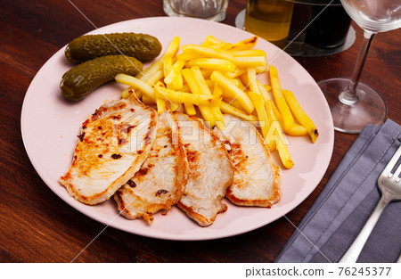 Close up of pork loin with potato and pickle at plate 76245377