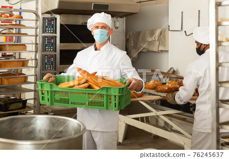 Portrait of baker in protective mask with fresh bread at bakery Portrait of baker in protective mask with fresh bread at bakery 76245637