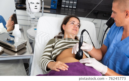 Woman getting hardware body treatment in aesthetic cosmetology clinic 76245773