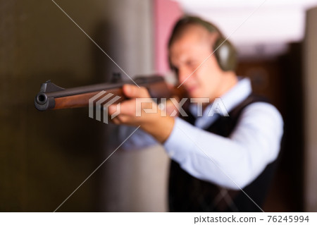 Muzzle of single barrelled shotgun on blurred background of aiming man 76245994