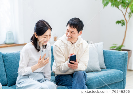 A middle-aged couple watching a smartphone in the living room A middle-aged couple watching a smartphone in the living room 76246206