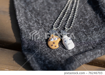 Set of best friends cookie and milk necklace pendant shoot outside in a summer day closeup. Selective Focus Set of best friends cookie and milk necklace pendant shoot outside in a summer day closeup. Selective Focus 76246703