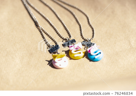 Three colored pendants best friends necklace shoot outside in a summer day closeup. Selective Focus 76246834