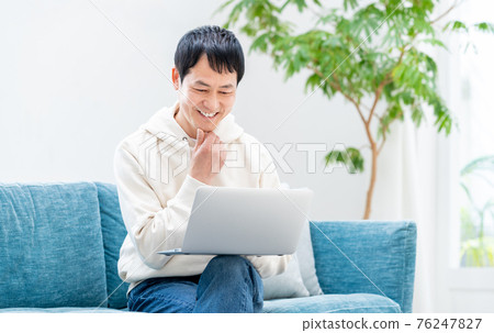 Middle man using a computer in the living room Middle man using a computer in the living room 76247827