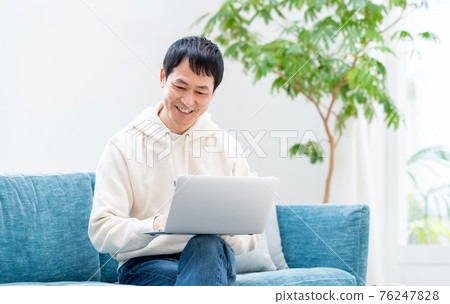 Middle man using a computer in the living room Middle man using a computer in the living room 76247828
