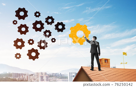 Businessman standing with back on house brick roof and drawing. Mixed media 76250142