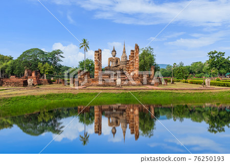 Buddha statue and Pagoda in ruined monastery complex at Wat Mahathat temple with reflection, Sukhothai Historical Park, Thailand 76250193
