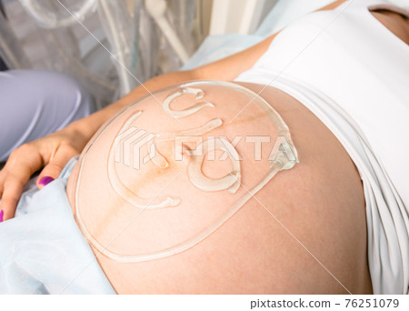 Smiley face painted with gel on stomach of a pregnant woman waiting for obstetric ultrasonography Smiley face painted with gel on stomach of a pregnant woman waiting for obstetric ultrasonography 76251079