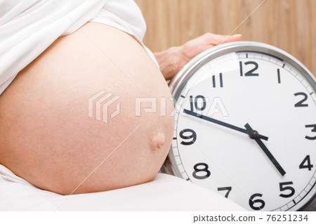 Pregnant woman with clock - final weeks of pregnancy concept Pregnant woman with clock - final weeks of pregnancy concept 76251234