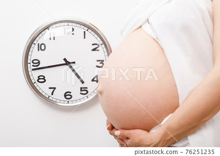 Pregnant woman with clock - final weeks of pregnancy concept 76251235