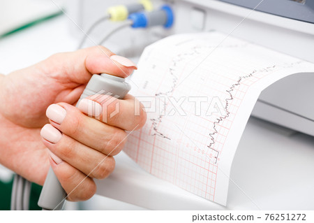 Pregnant woman performing cardiotocography CTG monitoring fetal heartbeat close-up 76251272