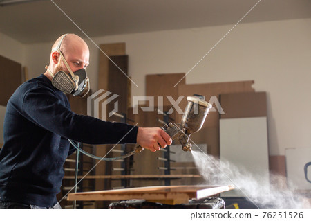Staining a wood with white spray gun, application of flame retardant ensuring fire protection, airless spraying device, industrial concept 76251526