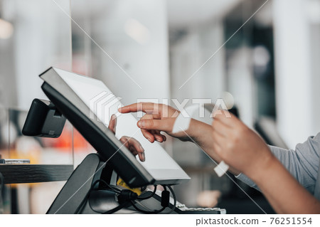 Young saleswoman doing process payment on touchscreen POS, counting sale in the cash register, finance concept Young saleswoman doing process payment on touchscreen POS, counting sale in the cash register, finance concept 76251554