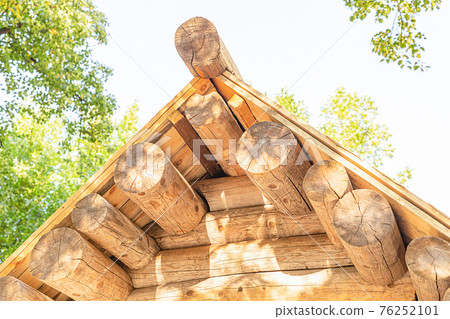 wooden log house with a sloping roof on a sunny day 76252101