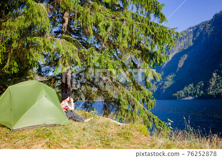 Woman traveler wild camping by a lake in Norway Woman traveler wild camping by a lake in Norway 76252878