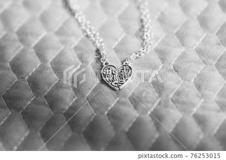 Pendant Best friends heart made up of two parts necklace shoot outside in a summer day closeup. Selective Focus 76253015