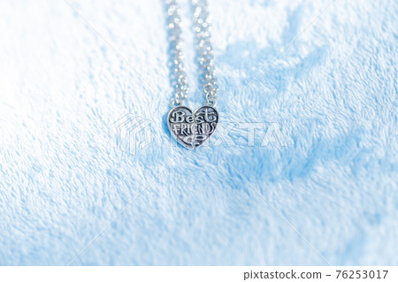 Pendant Best friends heart made up of two parts necklace shoot outside in a summer day closeup. Selective Focus 76253017