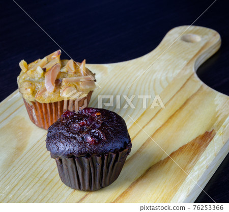 Chocolate muffin and banana cupcake on wooden tray. Chocolate muffin and banana cupcake on wooden tray. 76253366