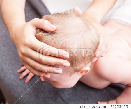 Little baby receiving osteopathic treatment of her skull and neck Little baby receiving osteopathic treatment of her skull and neck 76253495