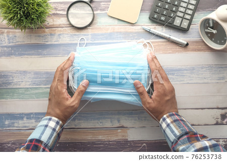 Close up of blue surgical masks on office deks Close up of blue surgical masks on office deks 76253738