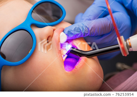 Little girl receiving dental filling procedure in pediatric dental clinic Little girl receiving dental filling procedure in pediatric dental clinic 76253954