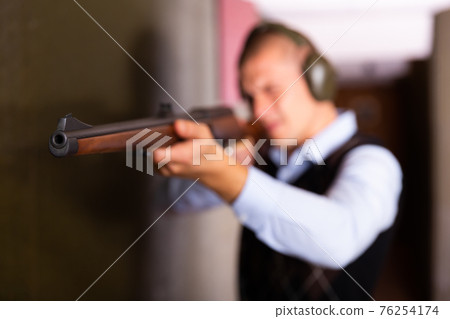 Muzzle of single barrelled shotgun on blurred background of aiming man 76254174