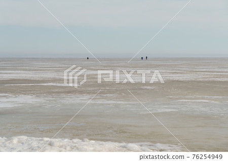 On ice of lake in the distance, fishermen are ice fishing in spring On ice of lake in the distance, fishermen are ice fishing in spring 76254949