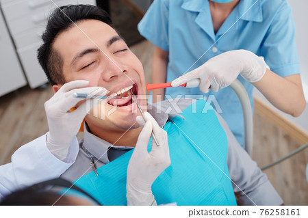 Dentist treating teeth of patient 76258161